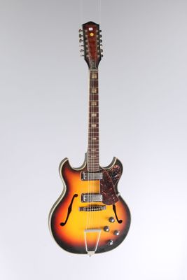 an electric guitar hanging from a string on a white wall