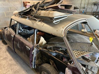 une voiture garée dans un garage, avec plein de choses empilées dessus