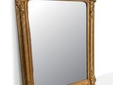 a gold framed mirror on the wall next to a white wall