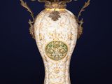 an ornately decorated vase on a stand against a dark blue background