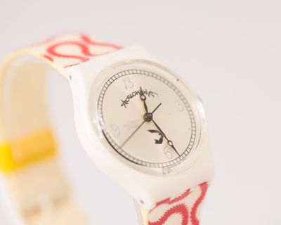 Quelqu'un porte une montre avec un motif rouge et blanc.