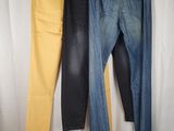 three pairs of jeans hanging on a clothes rack in front of a white curtain