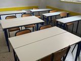 tables and chairs in an empty classroom with a window in the background