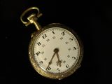 a small gold pocket watch on a black surface