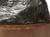 a bronze sculpture of a rock on a wooden base