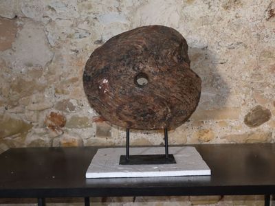 une sculpture en pierre posée sur une table devant un mur de pierre