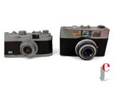 two old cameras sitting side by side on a white surface