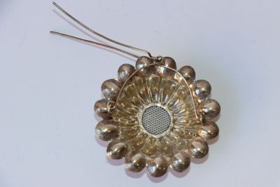 une broche en forme de fleur argentée posée sur une surface blanche