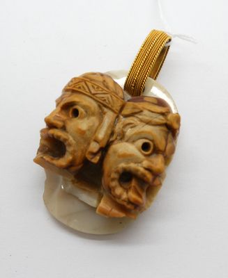 une image représentant deux visages sculptés suspendus à un collier