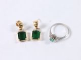 two emerald and diamond earrings and a ring on a white surface