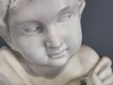 a small statue of a boy holding something in his hands