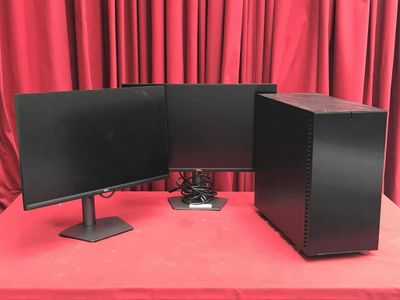 deux écrans d'ordinateur posés sur une table rouge, à côté d'un rideau rouge