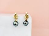 a pair of black pearl earrings with gold leaves on them