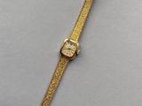 une montre en or posée sur une surface blanche