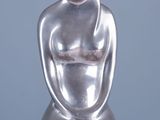 une statue en argent représentant une femme assise sur une table