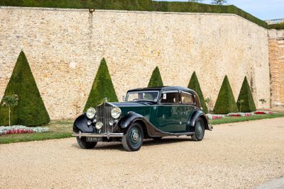 a vintage car that is parked in front of a stone wall
