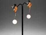 a pair of earrings with white pearls on a black stand