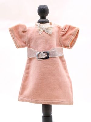 robe rose posée sur un présentoir à mannequin, ornée d'un nœud blanc