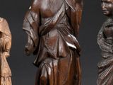 three carved wooden figures of women and a man on a table
