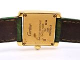 a gold watch with a green strap on a white surface