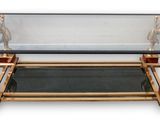 une table basse avec un plateau en verre et un piètement doré