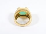 a close up of a gold ring with a green stone in it