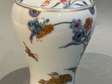 a white vase with a bird and flowers on it