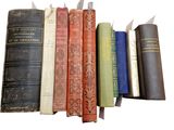 several old books are lined up in a row on a white surface
