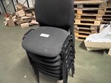 une pile de chaises dans un entrepôt, avec des palettes en arrière-plan