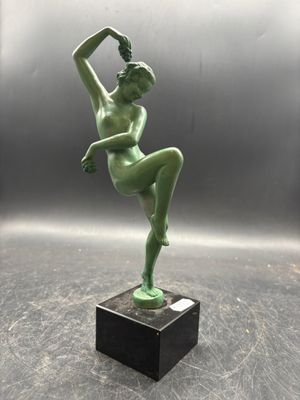 statue of a female dancer on a marble base on a gray background