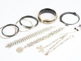 de nombreux bracelets et bagues en argent posés sur un fond blanc