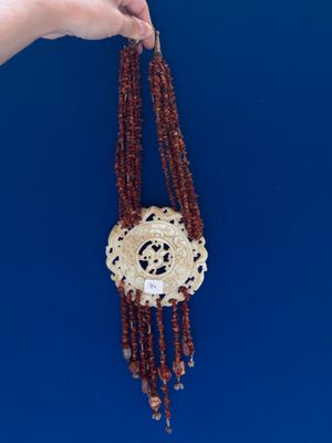 a person holding a necklace with beads hanging from it