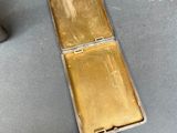 a gold cigarette case sitting on a table next to a lighter