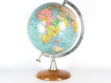 un petit globe terrestre posé sur un socle en bois, sur fond blanc