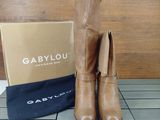 tan leather boots with tassels and a box on a tile floor