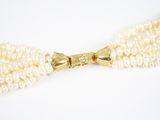 un gros plan sur un collier de perles blanches orné d'un nœud doré