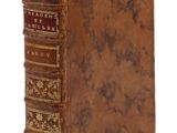 un vieux livre à la couverture brune posé sur une surface blanche
