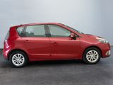 the small red car is parked in a room with a gray wall