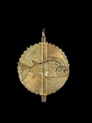 a close up of a gold pendant with a fish on it