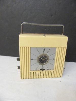 une petite horloge jaune posée sur une table blanche