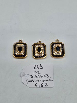 three gold and black glass pendants on a white surface