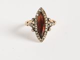 une bague en or sertie d'une pierre rouge entourée de petits diamants