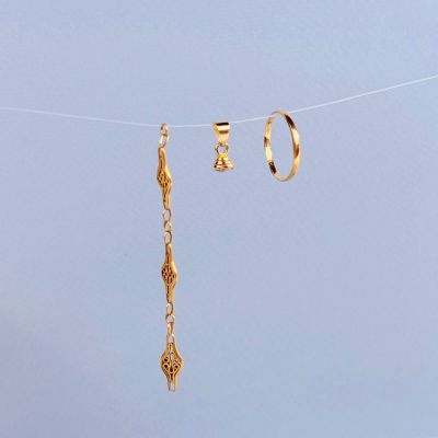 des boucles d'oreilles en or suspendues à une corde à linge, avec un ciel bleu en arrière-plan