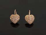 a pair of gold and diamond heart earrings on a black surface