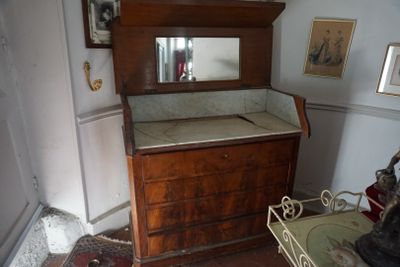 une commode dans un coin de la pièce, avec des tableaux accrochés au mur
