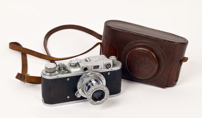 un appareil photo et un étui en cuir marron posés sur une surface blanche
