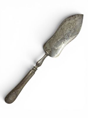 an old silver spoon with a metal handle on a white surface