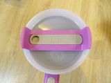 a plastic bowl with a pink handle on a wooden table