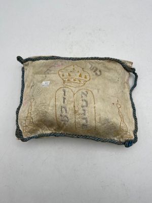 an old pillow with a crown on it sitting on a table