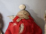 three small dolls are lined up against a wall